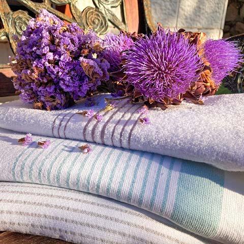 Stacked striped peshtemal towels with purple flowers outdoors